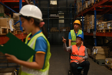 The handicapped supervisor in a wheelchair inspects the overview work in a warehouse. logistic...
