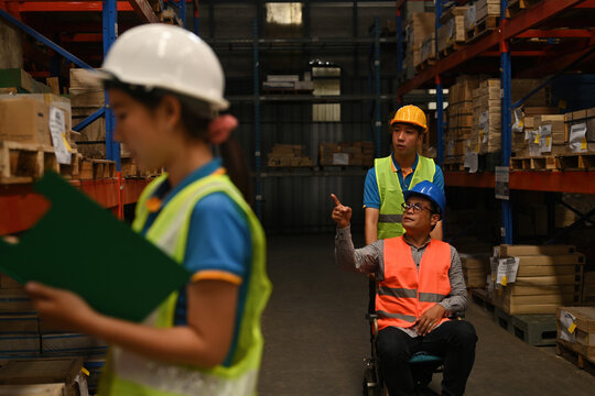 The handicapped supervisor in a wheelchair inspects the overview work in a warehouse. logistic business export management concept
