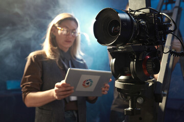 Portrait of female director overseeing video production and using digital tablet, copy space
