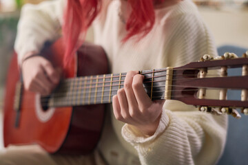 Close-up of young talented female musician playing acoustic guitar in front of camera while...