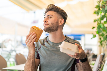 Young handsome man taking fried chips and takeaway box food