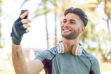 Young handsome man wearing sport wear and taking a selfie with the mobile