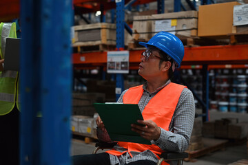 A senior warehouse supervisor with a disability in a wheelchair checks the stock inventory in a...