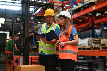 Two Warehouse workers examining the result on a document in logistics distribution warehouse