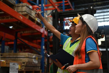 Two warehouse workers do a stocktaking of product management on shelves in the warehouse. Physical...