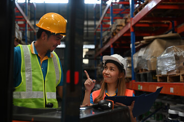 Close-up with Warehouse operator woman talking to forklift truck driver in a warehouse