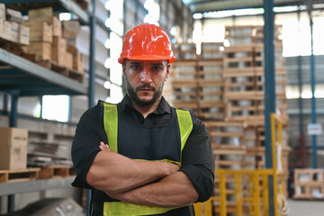 Portrait of a Handsome and Smart Caucasian warehouse worker standing in warehouse with his arm crossed and looking at camera