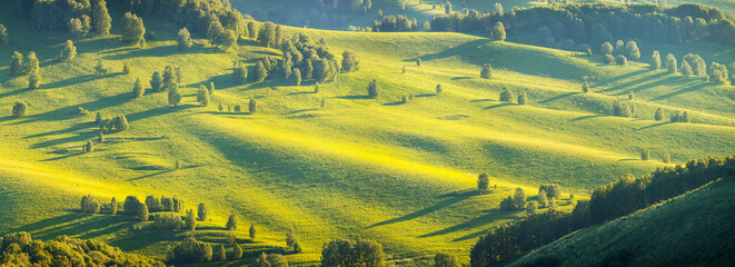 Green hillsides in the evening light, spring greenery, panoramic view	