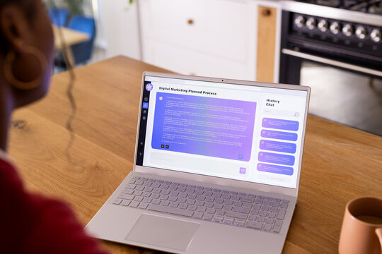 Using AI chatbot on laptop, African American young woman wearing headphones