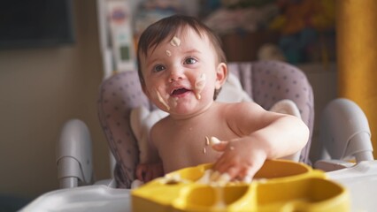 baby eats dirty. happy family a kid toddler concept. baby girl dirty sitting messing with food at...