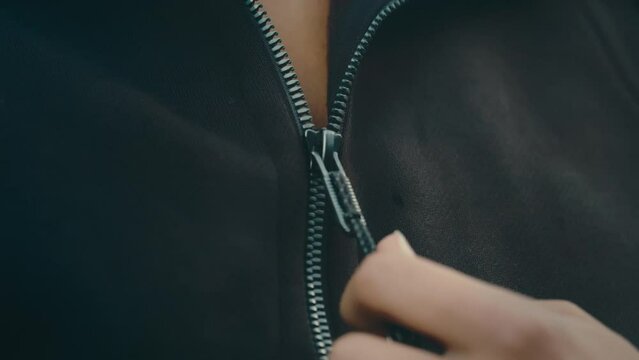 Woman pulling down jacket zipper in extreme slow motion, close up 4k 800fps taking off hoodie