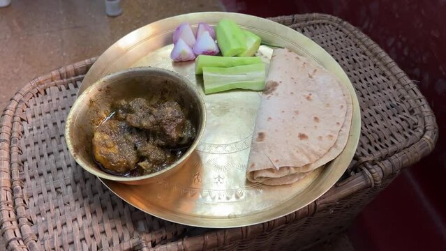 Shot of Roti and mutton served in brass plate