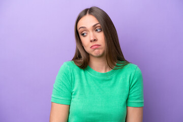 Obraz premium Young caucasian woman isolated on purple background making doubts gesture looking side
