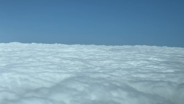 POV overflying a blanket of stratus clouds, shot from an airplane cabin. 4K 60FPS