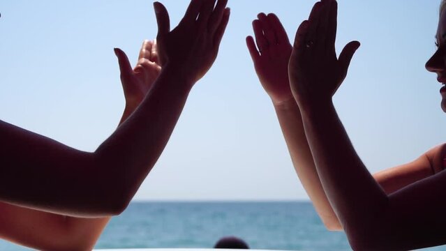 Rock paper scissors being played by two young woman. Close up view female hands playing stone, scissors and paper on sea background, funny carefree game. Friendship, dealing with conflict, having fun.