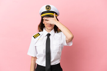 Airplane middle aged pilot woman isolated on pink background covering eyes by hands and smiling