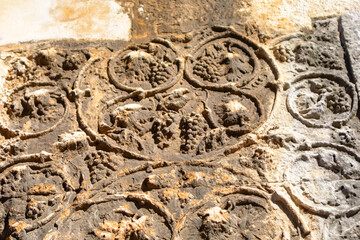 Bas-relief on the walls of the old city, Carved grapes on the wall, details of Romanesque architecture