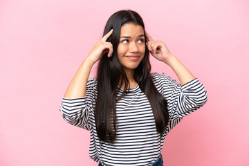 Young Colombian woman isolated on pink background having doubts and thinking