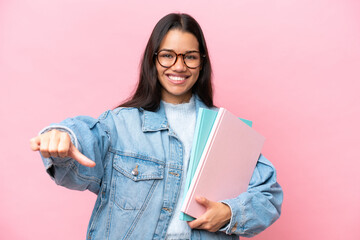 Young student Colombian woman isolated on pink background giving a thumbs up gesture