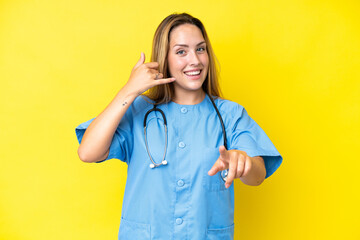 Young surgeon nurse woman isolated on yellow background making phone gesture and pointing front