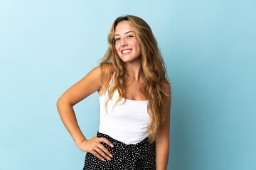 Young blonde woman isolated on blue background laughing