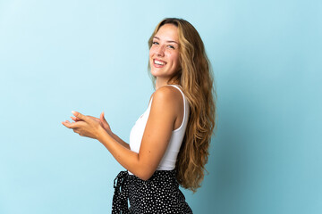 Young blonde woman isolated on blue background applauding