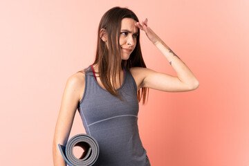 Young sport woman with mat over isolated background having doubts and with confuse face expression