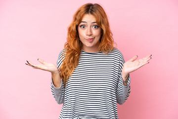 Young caucasian woman isolated on pink background having doubts while raising hands