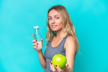 Young Russian woman isolated on blue background with an apple and with a bottle of water