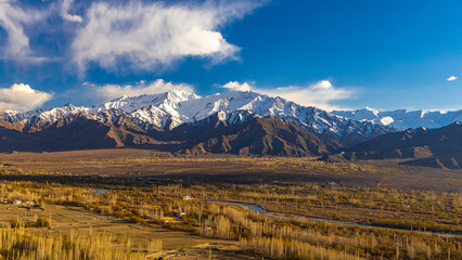 Panoramic view of Ladakh valley with blue Indus River flowing in the middle and snowcapped mountain...