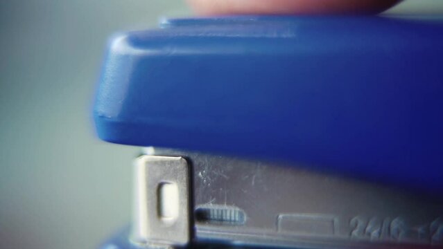 Macro close up shot, pressing on a blue stapler, super slow motion 120 fps, Full HD