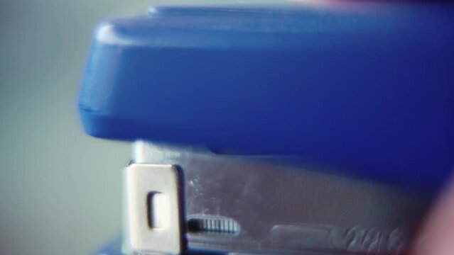Macro close up shot, pressing on a blue stapler, slow motion 120 fps, Full HD static video