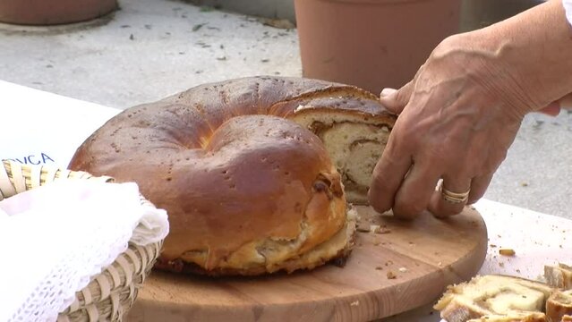 old woman cutting potica with knife, closeup of slovenian cake on wooden board