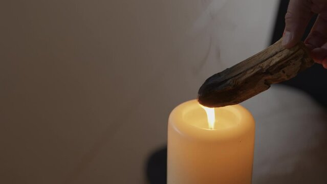 A person burning incense over a candle