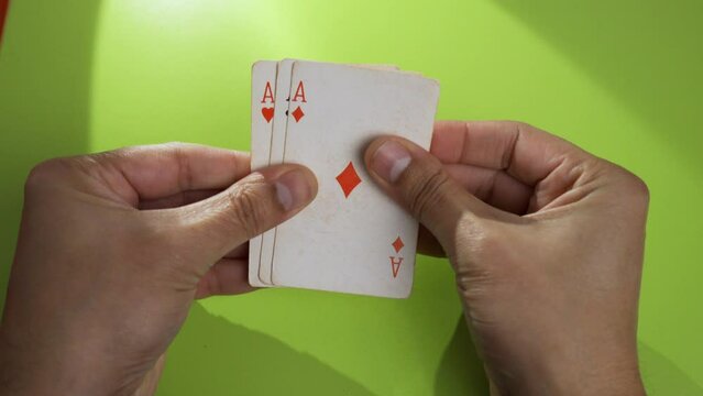 Closeup of a hand holding playing cards and looking at them