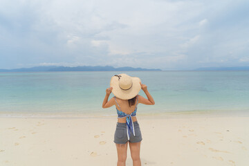 Happy Asian woman, a sexy Thai lady, relaxing and enjoying at turquoise sea near Phuket beach in summer during travel holidays vacation trip outdoors at natural ocean or island at noon, Thailand.