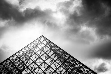 Black and white dramatic image of the Louvre pyramid in the city of Paris 