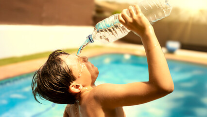 Boy drinking a bottle of water on a hot summer day