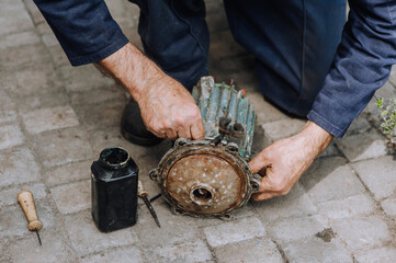 Male professional, electrician, electromechanic repairing an old rusty electric motor in a workshop. Photography, close-up portrait.