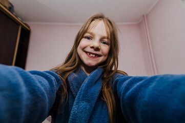 miling beautiful red-haired girl, funny teenager takes pictures of herself holding a camera, smartphone, telephone showing a grimace, smiling, making faces. Photography, portrait.
