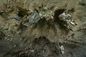 Natural stalactite and stalagmite rock stone cliff hang from cave ceiling in cave with lake river sea. Environmental explore. Landscape background. Erosion