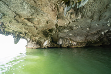 Natural stalactite and stalagmite rock stone cliff hang from cave ceiling in cave with lake river sea. Environmental explore. Landscape background. Erosion