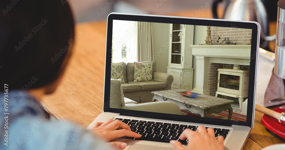 Wall mural Image of person using laptop with house sitting room interiors displayed on screen