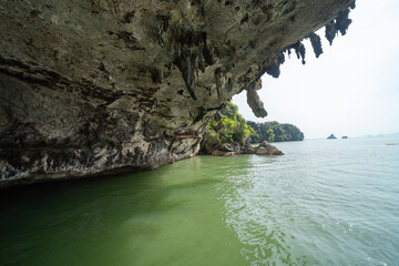 Natural stalactite and stalagmite rock stone cliff hang from cave ceiling in cave with lake river...