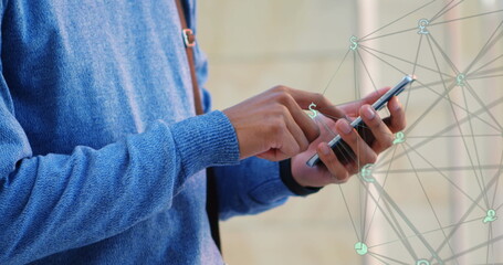 Image of a web of connections over Caucasian man standing on a street, using smartphone