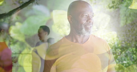 Image of spots of light and trees over smiling senior african american man in garden