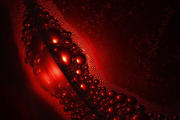 Burbujas de color rojo sobre el círculo de cristal con agua y jabón, flotan en la superficie...