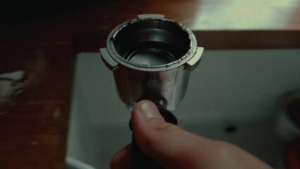 Set on a fixed view, the camera captures the journey of a coffee pot from emptying its contents, followed by cleansing with water and placement back onto the stack.