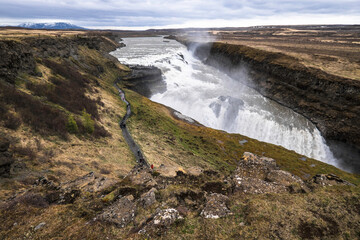 Famous Gulfoss waterfall in the Golden Circle in South Iceland. Tourists walk on a path to the viewpoint. Wide landscape view