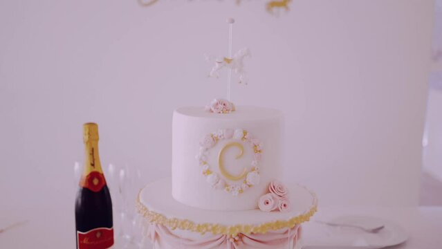 Elegant white celebration cake with gold accents and initial 'C' topper